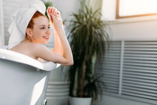 Femme sensuelle avec de longs cheveux de gingembre relaxant dans l'eau avec de petites fleurs — Photo