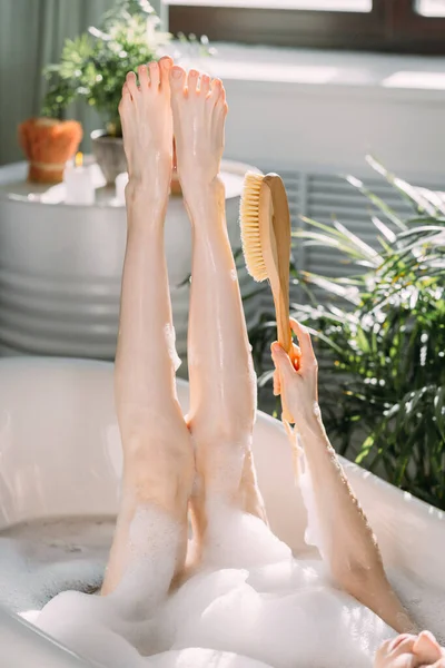 Cropped shot of bathing woman with slim legs raised in air indoor — Stock Photo, Image