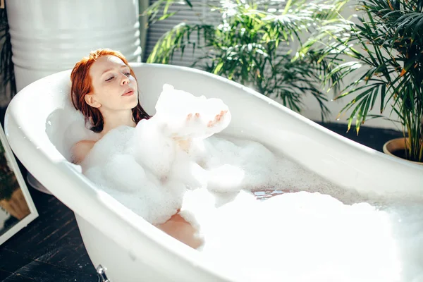 Retrato de una joven feliz jugando con espuma en la bañera — Foto de Stock