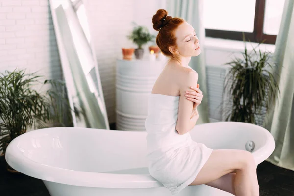 Redhead woman preparing foam bath in spacious bathroom with green plants — Stock Photo, Image