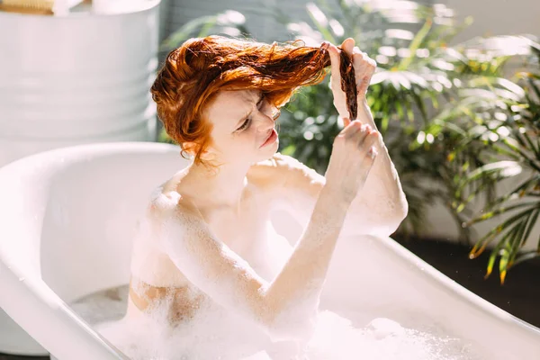 Портрет счастливой молодой женщины, играющей с пеной в ванной — стоковое фото