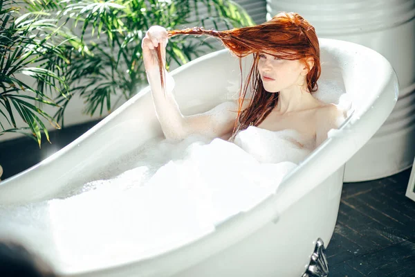 Porträt einer glücklichen jungen Frau, die mit Schaum in der Badewanne spielt — Stockfoto