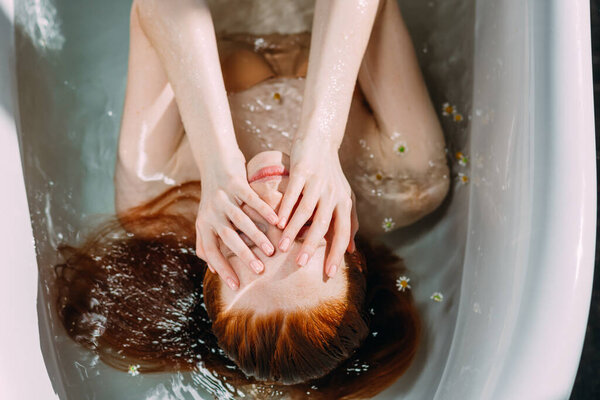 Красивая соблазнительная рыжеволосая девушка с голыми плечами в ванной.