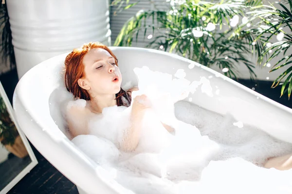 Retrato de una joven feliz jugando con espuma en la bañera — Foto de Stock