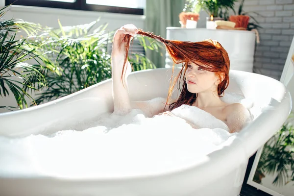 Retrato de una joven feliz jugando con espuma en la bañera — Foto de Stock