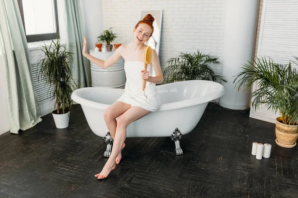 욕조에서 편안하게 목욕 할 때 브러시를 사용하여 노래하는 즐거움을 누리는 여자 — 스톡 사진