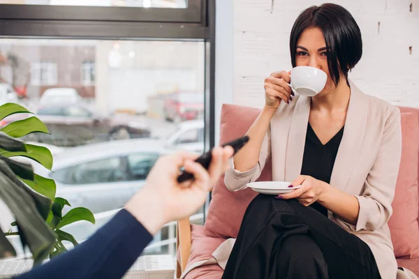 Joven impresionante hermosa chica está bebiendo té durante la entrevista — Foto de Stock