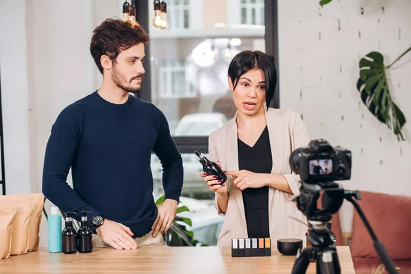 Mujer emocional están sosteniendo una botella con una loción y hablando con la cámara — Foto de Stock