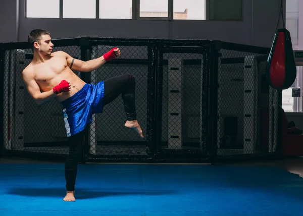 Boxer ziet er sterk en krachtig uit, oefent schoppen, warmt op voor het spel indoor — Stockfoto