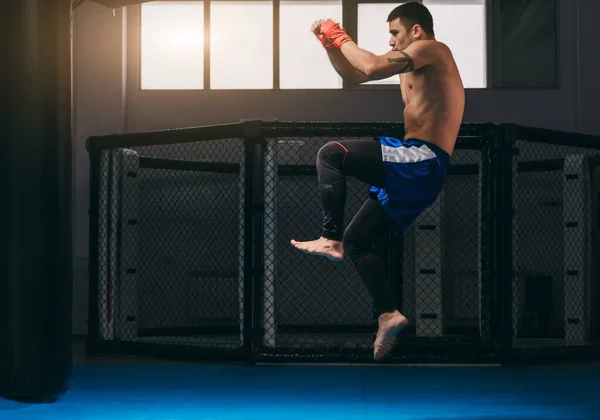 Boxer ziet er sterk en krachtig uit, oefent schoppen, warmt op voor het spel indoor — Stockfoto