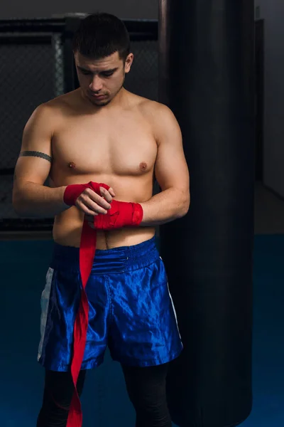El boxeador masculino exitoso envuelve puños con vendajes protectores, se prepara para luchar —  Fotos de Stock