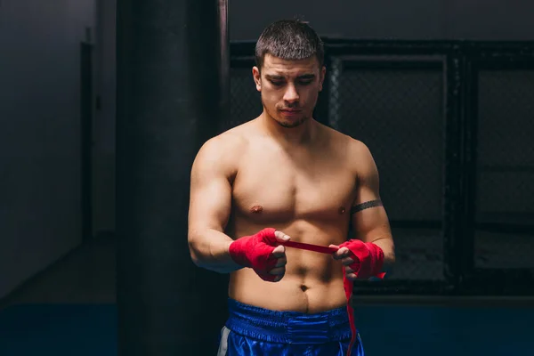 Successful male boxer wraps fists by protective bandages, prepares for fighting — Stock Photo, Image