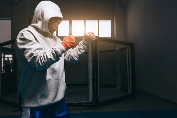 Oigenkännlig boxare i grå luvtröja med huva ner över ögonen tränar i gym. — Stockfoto