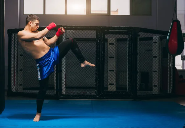 Boxer se ve fuerte y poderoso, practica patadas, se calienta antes del juego en interiores —  Fotos de Stock