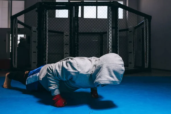 Onherkenbare kerel in sport hoodie doet push-ups op vuisten. — Stockfoto