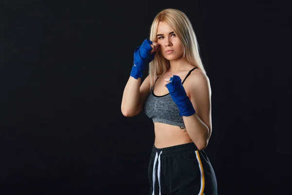 Determined blonde female boxer in blue handwraps gets prepared for fight