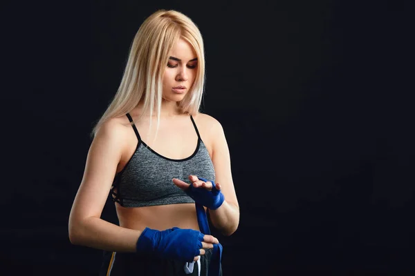 Female athlete dressed in tank top wrapping his fists by blue elastic bandages — Stock Photo, Image