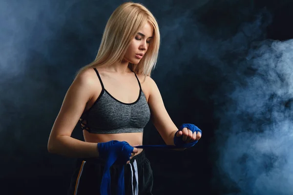 Blond vrouwelijke atleet is oefenen in de verdediging op donkere rokerige achtergrond. — Stockfoto