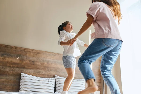 Femme heureuse sautant sur le lit avec sa fille — Photo