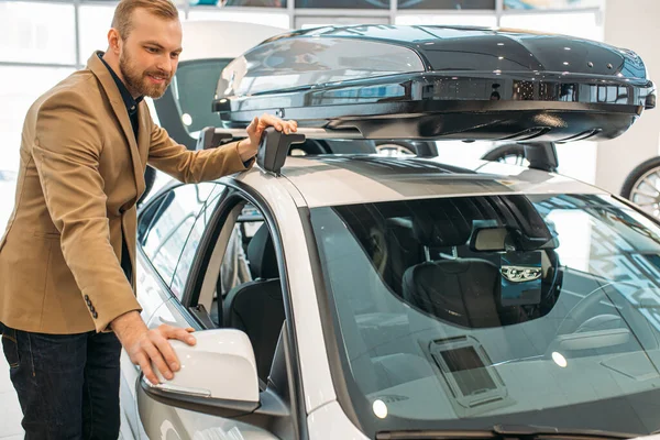 Genç beyaz adam satın almadan önce yeni arabayı inceliyor.