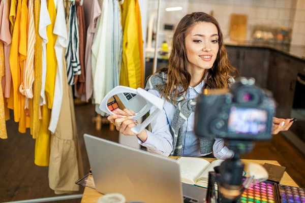 Genç beyaz kadın, palet kozmetiğini kameraya gösteriyor.