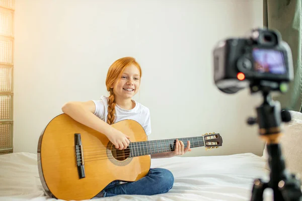 Mooie schattige Kaukasische kind blogger spelen gitaar op camera — Stockfoto