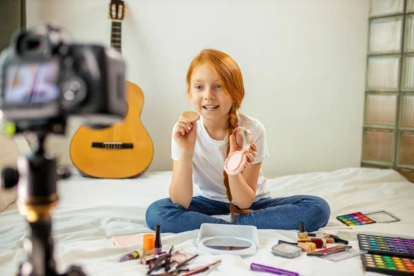 Enthusiastic little blogger show cosmetics at camera — Stock Photo, Image