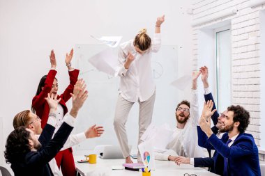 Modern ofiste zaferi kutlayan mutlu iş ekibi.