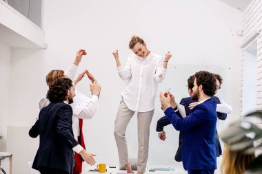 Neşeli iş ekibi modern ofiste zaferi kutluyor.