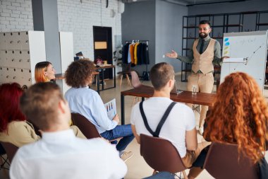 Tecrübeli genç işletme koçu idari yöneticilere sunum yapıyor.