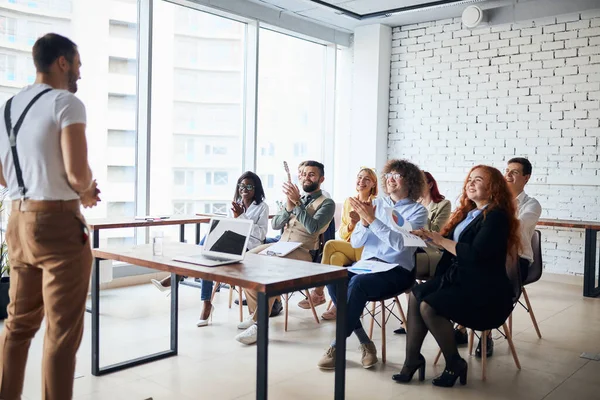 Schöner Geschäftsmann diskutiert neues Geschäftsprojekt mit den Mitgliedern seines Teams in modernem Büro — Stockfoto