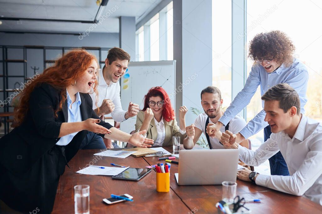 Happy business people gathered around table in office