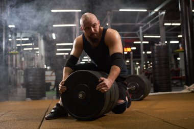 Powerlifter spor salonunda demir diskleri değiştiriyor.