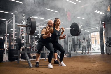 Antrenörle çalışan kadın halterci.