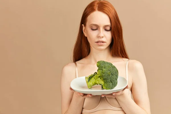 Donna anoressica in intimo piatto di sostegno con broccoli crudi isolati in studio — Foto Stock