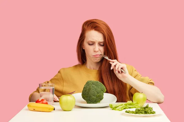 Pflanzliche Ernährung. Traurige langweilige Frau hält Brokkoli auf Gabel und macht Fratze — Stockfoto