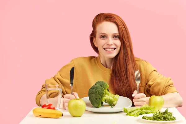 Sağlıklı yemek ve brokoli ile masada oturan güzel kızıl saçlı beyaz kadın. — Stok fotoğraf