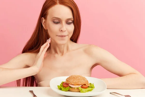 Mujer flaca pelirroja con ojos codiciosos lista para comer hamburguesa. —  Fotos de Stock