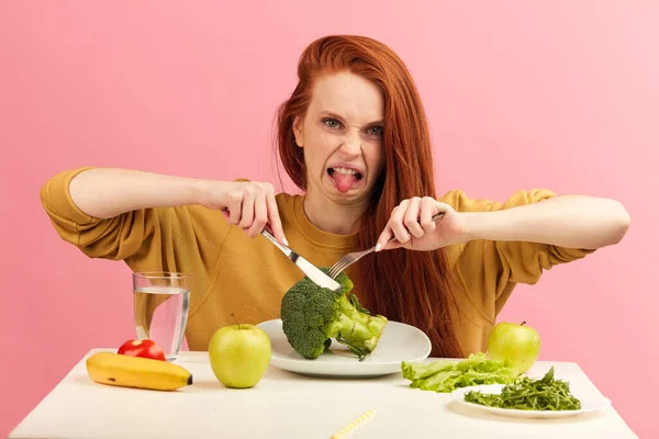 Vegetable diet. Sad dull woman holding broccoli on fork while making grimace