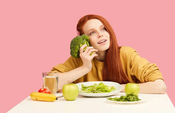 Slim mutlu kadın, brokoli ile masada oturuyor lezzetli pasta rüyaları görüyor, baştan çıkarıcı. — Stok fotoğraf