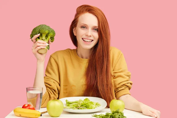 Bella rossa donna caucasica seduta a tavola con cibo sano e broccoli — Foto Stock