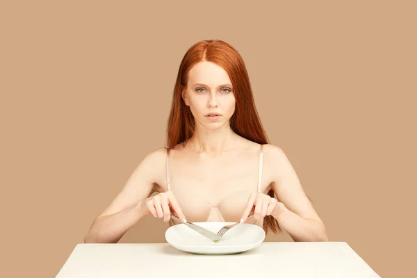 Femme rousse mangeant un pois vert avec fourchette et couteau. Concept de régime alimentaire. — Photo