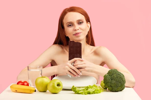 Anorexi kobieta czuje się szczęśliwy podczas jedzenia czekolady zamiast zdrowych warzyw. — Zdjęcie stockowe