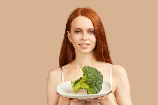 Skinny woman in underwear holding broccoli, licking, wants to eat it very much