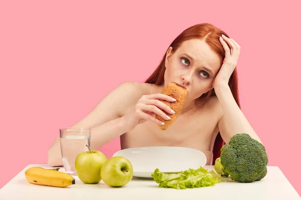 Donna apatica annoiata mangia croissant fissando nello spazio ignorando frutta cruda — Foto Stock