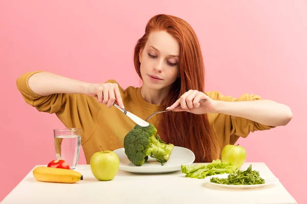 Hübsche rothaarige Kaukasierin sitzt am Tisch mit gesundem Essen und Brokkoli — Stockfoto