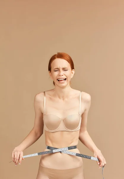 Flaco modelo femenino sufriente en ropa interior desnuda atada a la cintura con cinta métrica —  Fotos de Stock