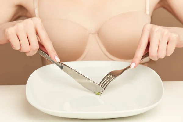 Eating Disorder, Anorexia. Woman eats one green pea with fork, close up. — Stock Photo, Image