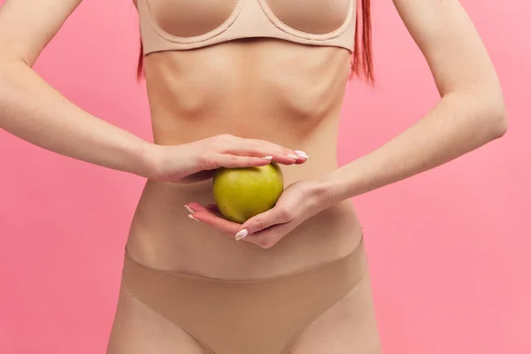 Mulher magro com costelas salientes segurando maçã verde isolado em rosa, macro — Fotografia de Stock