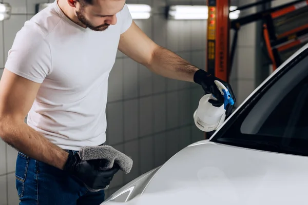 Impresionante joven sostiene el paño de microfibra en la mano y pule el coche. — Foto de Stock